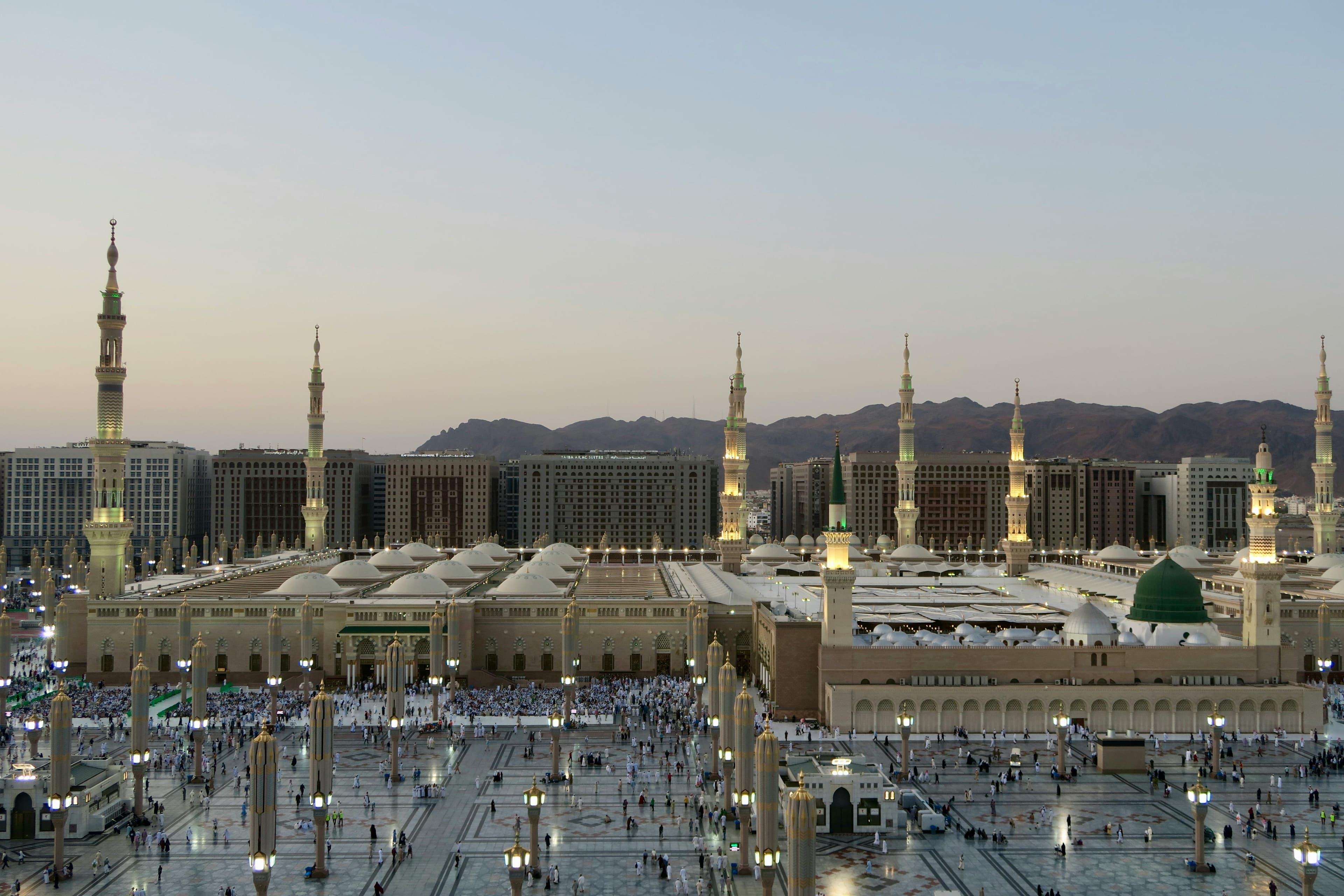 Al-Masjid an-Nabawi at twilight — domes, minarets, green dome, and courtyard